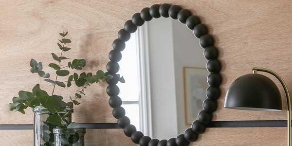 A round, black beaded mirror on a wall.
